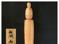 Shitō Shōzan (志形尚山) Hokage 灯影 Meaning Flicker of Light  This Kokeshi has been featured in many books, including self published book by Shouzan. It stands 16 1/4 tall. Her name is Hokage meaning Flickering of Light. I could see how the slender elongated body, with the nihongami hair  resemble a candlestick of sorts.